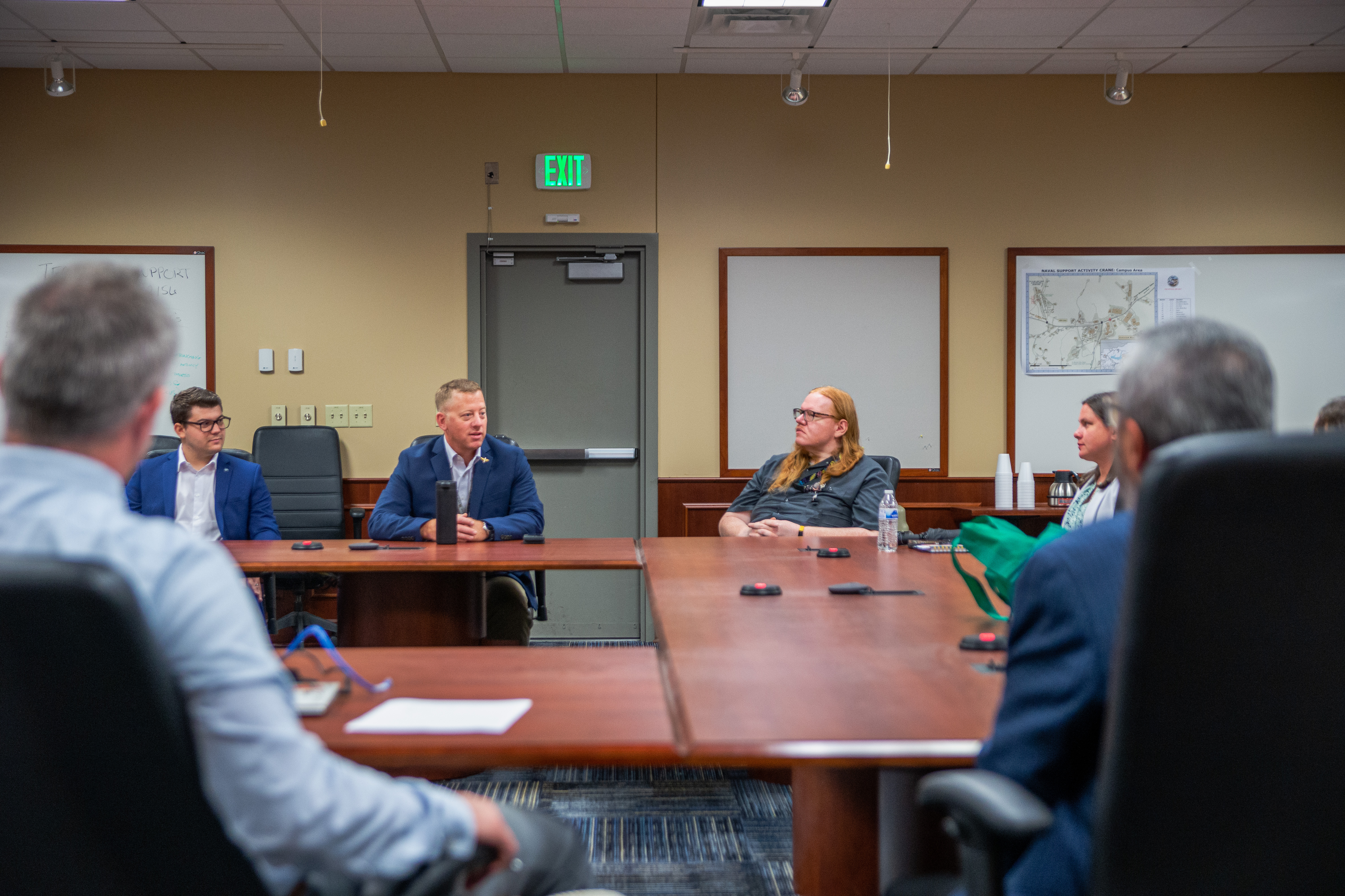 A group of people sit around a large table in an office. 